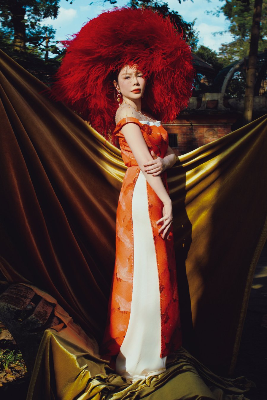 Phần cổ và tay áo dài cũng được NTK lược bỏ thay vào đó là cổ được sử dụng tulle xuyên thấu và đính kết những hạt nhỏ li ti trông sẽ giúp cho nữ diễn viên trông thanh thoát và lung linh hơn dưới ánh nắng chiều. Phần bắp tay được khéo léo thiết kế choàng nhẹ tinh tế.