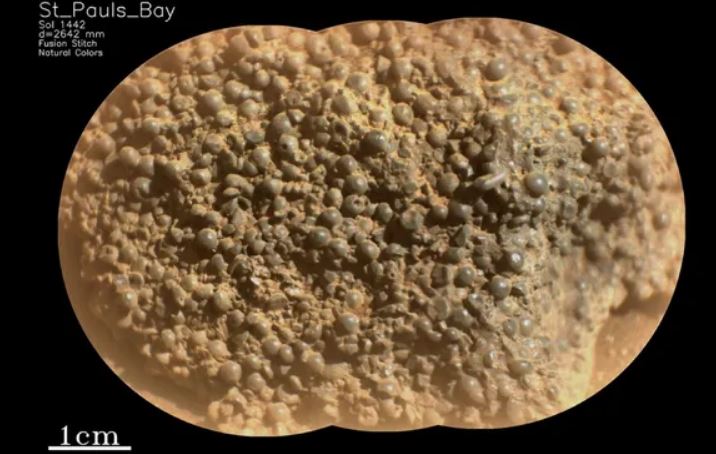 Cận cảnh một tảng đá sao Hỏa bất thường được tạo thành từ hàng trăm quả cầu tròn tối màu dính lại với nhau.