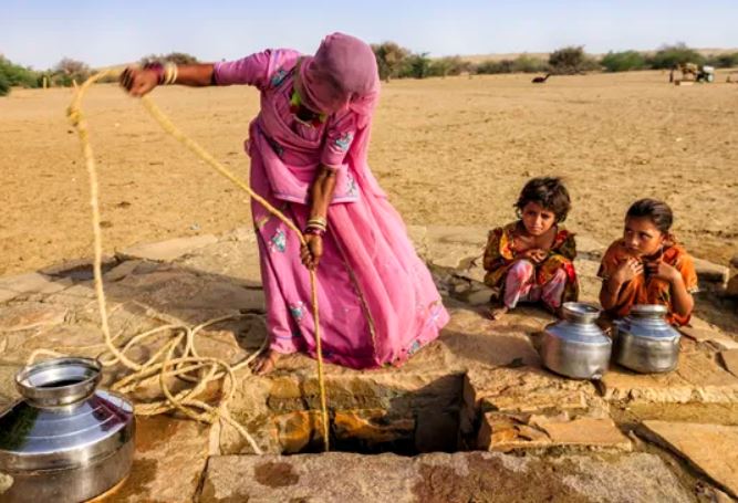 Một người phụ nữ và hai đứa con đang lấy nước từ giếng ở sa mạc Thar.