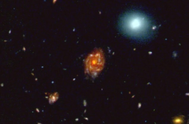 Big Wheel màu đỏ - thiên hà đĩa xoắn ốc cùng kiểu với Ngân Hà - cách chúng ta hơn 11 tỉ năm ánh sáng nhưng trông lớn hơn nhiều so với thiên hà màu xanh sáng nằm cách chúng ta chỉ 1,5 tỉ năm ánh sáng - Ảnh: NASA/ESA/CSA