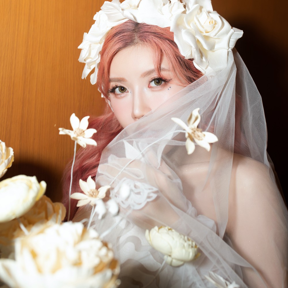 Chiếc váy cưới kết màn nữ ca sĩ mặc là sáng tạo đặc biệt của bộ sưu tập. Vẫn là màu trắng truyền thống, IDY Atelier tạo điểm nhấn với lớp voan hoạ tiết hoa hồng phủ toàn bộ váy.  Sự kết hợp sáng tạo này phát huy ưu điểm mềm mại, bồng bềnh của chất liệu voan, tạo độ mềm, nhẹ nhàng cho dáng váy phồng. Form váy được trau chuốt kỹ lưỡng trong khâu cắt, may, định hình giúp tôn dáng người mặc.