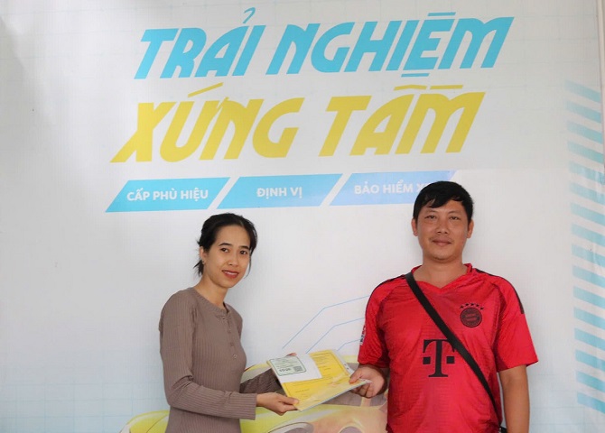 Nhân viên tư vấn trao phù hiệu, lệnh vận chuyển và các giấy tờ liên quan cho một lái xe vừa hoàn thành thủ tục tham gia hợp tác xã. 