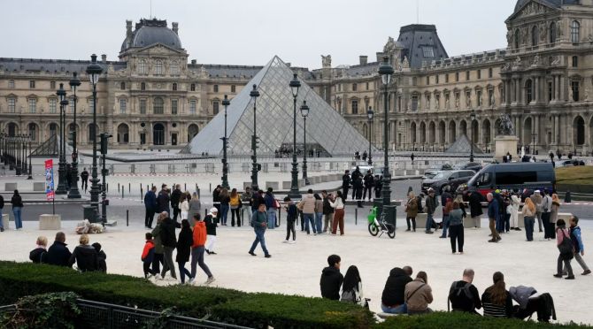 Khách du lịch và du khách đi bộ trước bảo tàng Louvre sau khi bảo tàng đóng cửa sau vụ cướp vào Chủ Nhật. Ảnh: NBCnews.