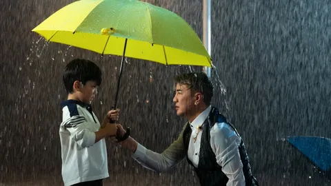 Đàm Vĩnh Hưng và con trai Polo Huỳnh dắt tay nhau đi trong mưa